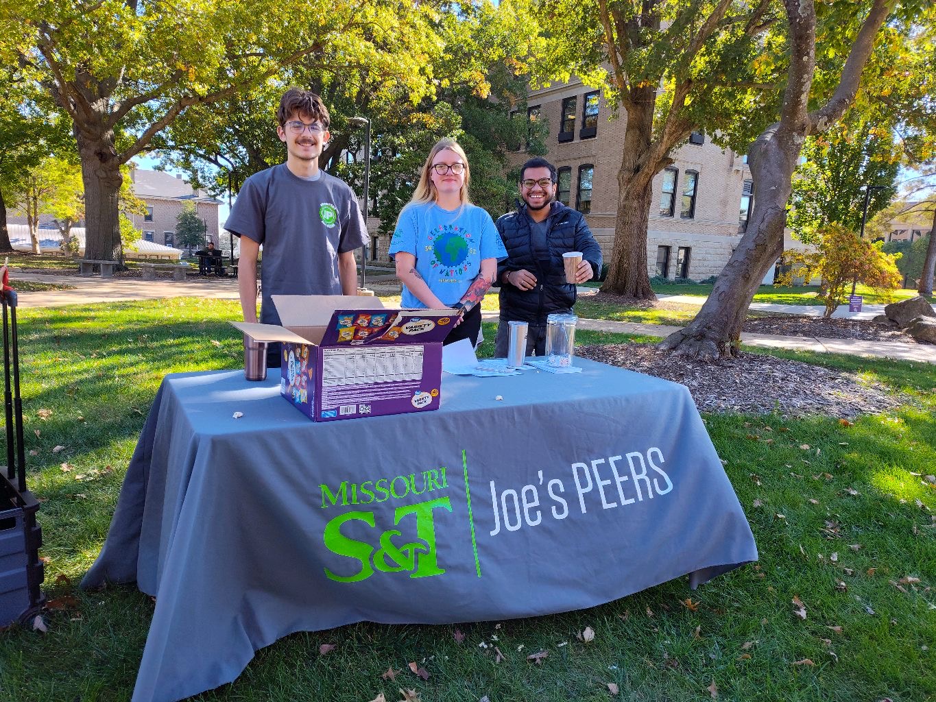 three students stand behind a table