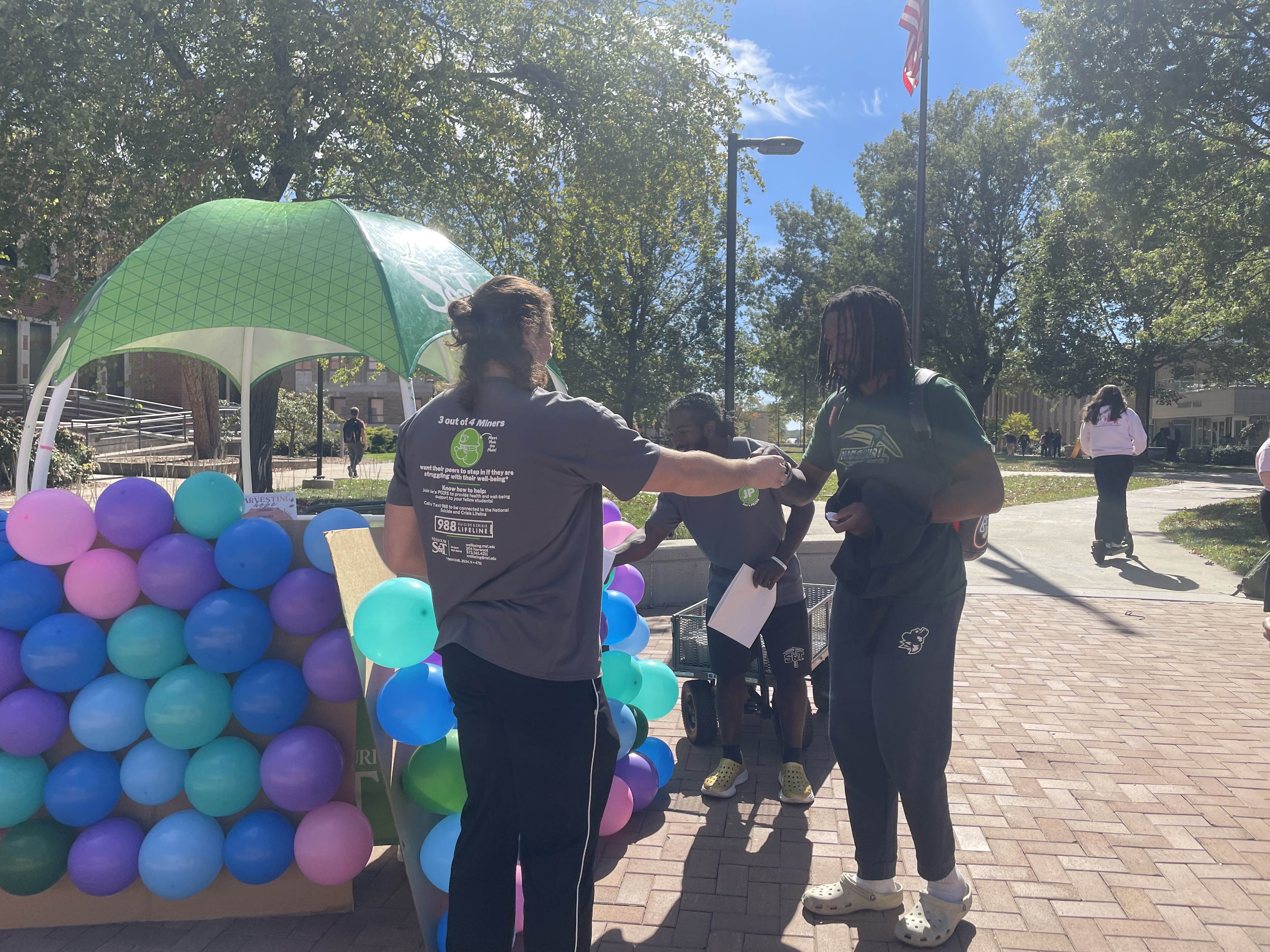 three students talking in front of balloons