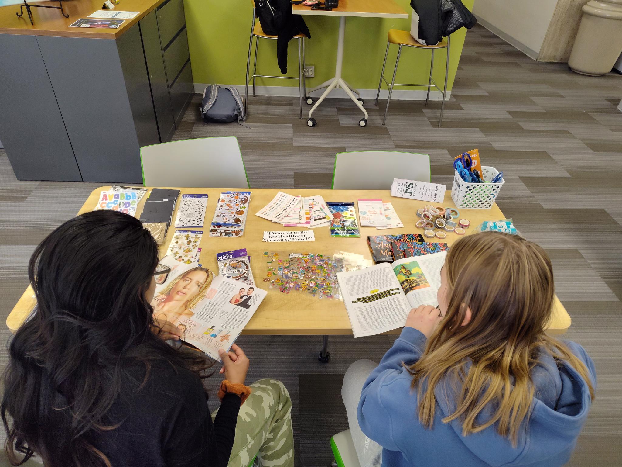 two students crafting with magazines